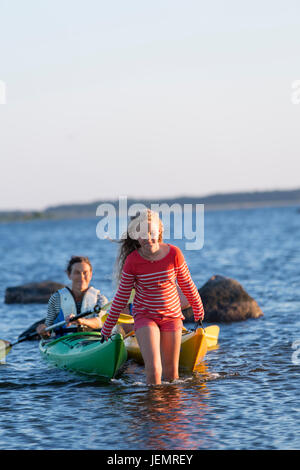 Mädchen ziehen Kajaks im Meer Stockfoto