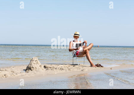 Reifer Mann Buch am Strand lesen Stockfoto