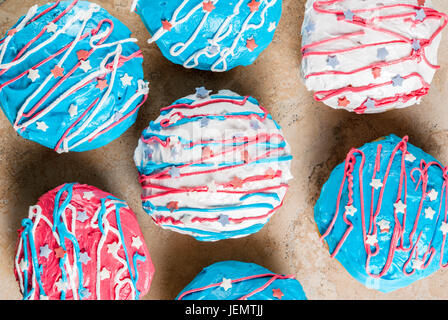 Essen für Independence Day. 4th of July. Festliches Frühstück: traditionelle amerikanische Donuts mit Glasur in den Farben der USA Flagge, blau, rot, weiß. Auf leichte sto Stockfoto