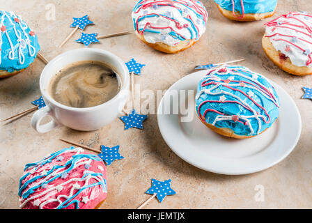 Essen für Independence Day. 4th of July. Festliches Frühstück: traditionelle amerikanische Donuts mit Glasur in den Farben der USA Flagge, blau, rot, weiß. Tasse Kaffee Stockfoto