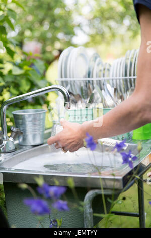 Frau Geschirrspülen im Garten Stockfoto