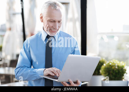 Positiv erfreut männliche Person mit seinem laptop Stockfoto