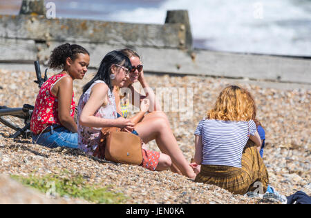 Eine Gruppe von jungen Menschen verschiedener Ethnien auf einem Strand zu genießen Hot tragen am Meer im Sommer in Großbritannien. Stockfoto