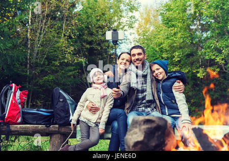 Familie mit Smartphone unter Selfie nahe am Lagerfeuer Stockfoto