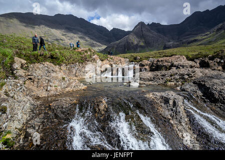 Black Cuillin und Touristen, die den Fairy Pools, Abfolge von Wasserfällen in Glen Brittle auf der Isle Of Skye, Schottisches Hochland, Schottland, UK Stockfoto