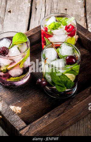 Satz von traditionellen Sommer erfrischende Getränke Beere Mojito. Mit Limette Minze, Brombeeren, Himbeeren und Kirschen. Mit den Zutaten im tray Stockfoto