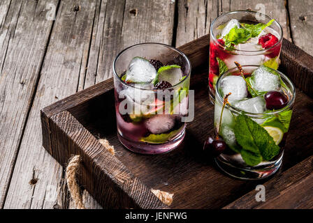 Satz von traditionellen Sommer erfrischende Getränke Beere Mojito. Mit Limette Minze, Brombeeren, Himbeeren und Kirschen. Mit den Zutaten im tray Stockfoto