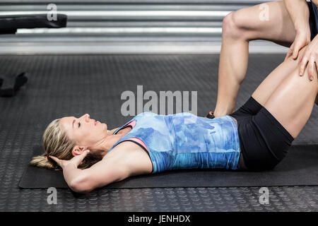 Männlichen Trainer Frau mit Sit-Ups zu unterstützen Stockfoto