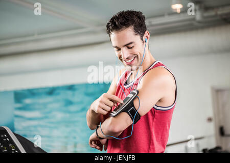 Lächelnder Mann auf Laufband mit smartphone Stockfoto