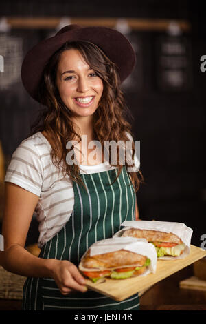 Lächelnd hält Sandwiches barista Stockfoto