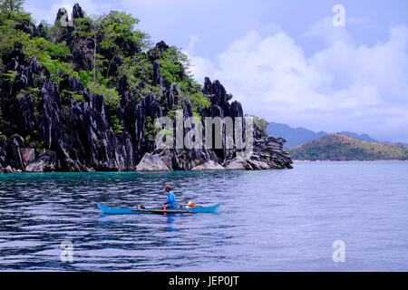 Ein Filipino Fischer Bootfahren in traditionellen Banka Auslegerboot entlang Alcatraz Riff in der Insel Coron in die Calamian Inseln im nördlichen Palawan auf den Philippinen Stockfoto