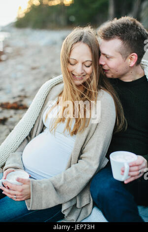 Junges Paar mit Drink am Strand Stockfoto