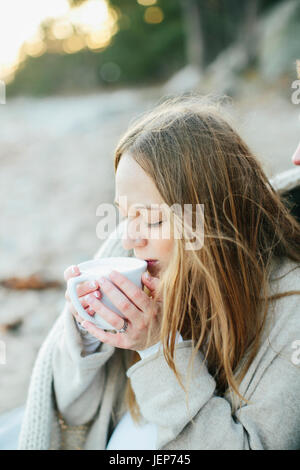 Junge Frau mit Drink am Strand Stockfoto