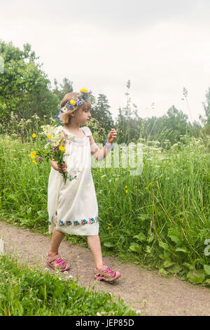 Mädchen tragen Blumen Kranz auf Wiese Stockfoto