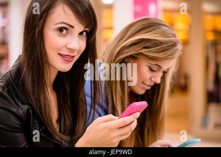 Zwei schöne Frauen, die mit ihrem Handy Stockfoto