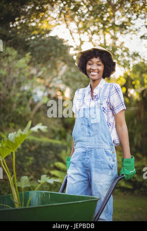 Lächelnde Frau drücken Schubkarre Stockfoto