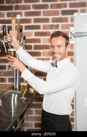 Gut aussehend Barkeeper Gießen einen pint Stockfoto