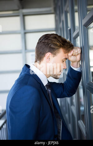 Müde Geschäftsmann stützte sich auf Tür Stockfoto