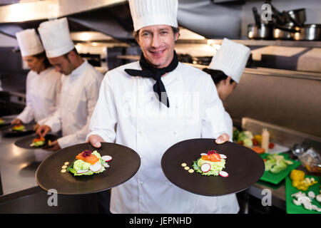Glücklich Chefkoch präsentiert seinen Lebensmittel-Tafeln Stockfoto