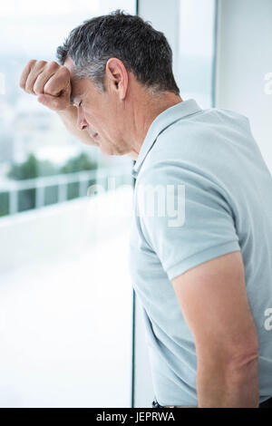 Gespannten Mann stützte sich auf Glasfenster Stockfoto