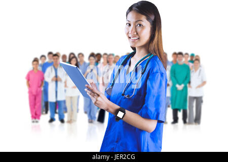 Das zusammengesetzte Bild im asiatischen Krankenschwester, die den Tablet-PC Stockfoto