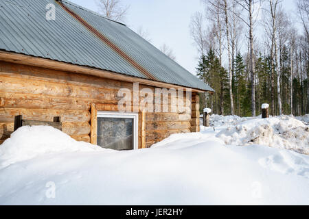 Blockhaus mit Schnee im Wald bedeckt Stockfoto