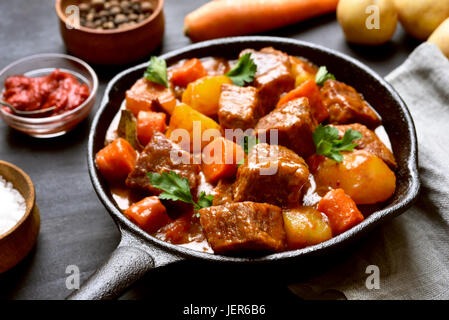 Rindfleisch geschmort mit Kartoffeln und Karotten in Gusseisen Pfanne, Nahaufnahme Stockfoto