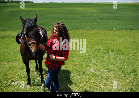 Junge hübsche Mädchen Aufenthalt mit Pferd auf einem Feld am sonnigen Tag. Stockfoto