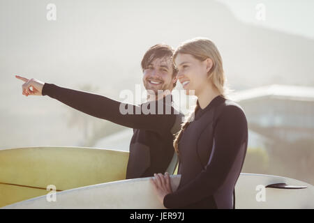 Paar mit Surfbrett stehend am Strand Stockfoto