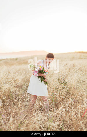 Frau mit Blumen auf Wiese gehen Stockfoto