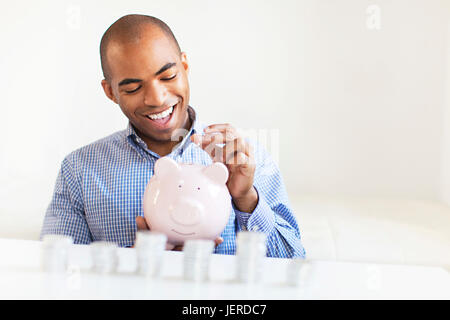 Junger Mann, Münze in Sparschwein Stockfoto