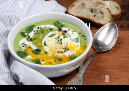 Püree Erbsensuppe mit pochiertem Ei, saure Sahne, Minze Blätter mit Gewürzen gewürzt. Stockfoto