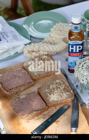 Corned Beef Sandwiches mit HP Sauce Flasche auf einem Steckbrett mit Besteck und Geschirr aus den 1940er Jahren. Stockfoto