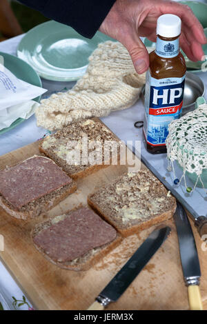 Corned Beef Sandwiches mit HP Sauce Flasche auf einem Steckbrett mit Besteck und Geschirr aus den 1940er Jahren. Stockfoto