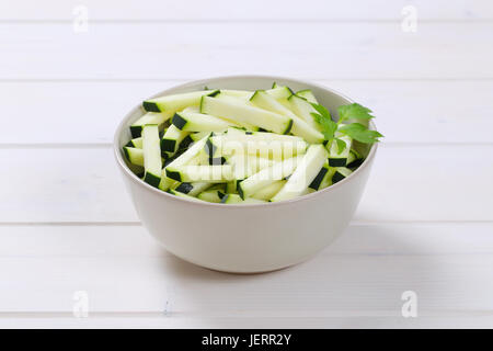 Schüssel mit Zucchini Streifen auf weißem Hintergrund aus Holz Stockfoto