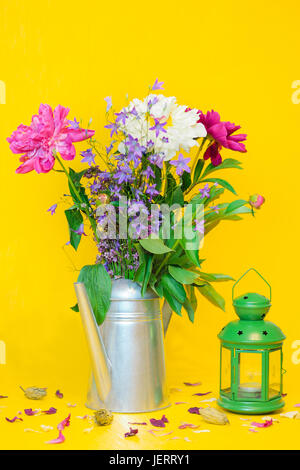Stillleben mit eine schöne weiße und violette Pfingstrosen-Strauß und eine grüne Laterne vor dem unscharfen gelb Hintergrund Stockfoto