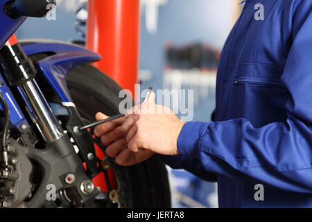 Motorrad-Mechaniker Hände Demontage Teile in einem Workshop mit Ausrüstung im Hintergrund Stockfoto
