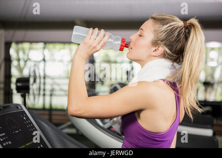 Frau am Laufband Trinkwasser in Turnhalle Stockfoto