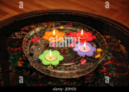 In der Nähe von schwimmenden bunte Blume geformte Kerzen im Glas von Schüssel. Stockfoto