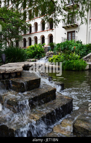 Ein Wasserfall entlang der Baum beschattet Riverwalk in San Antonio, Texas. Stockfoto