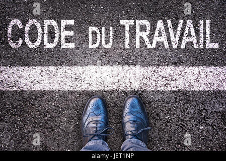 Code du Travail (Bedeutung Arbeitsgesetzbuch in französischer Sprache) geschrieben auf eine Asphalt-Straße-Hintergrund mit Beinen Stockfoto