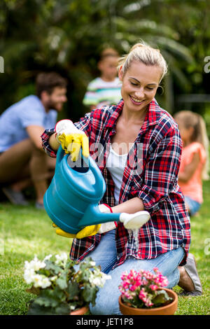 Frau, die Blumen auf dem Rasen im Garten gießen Stockfoto