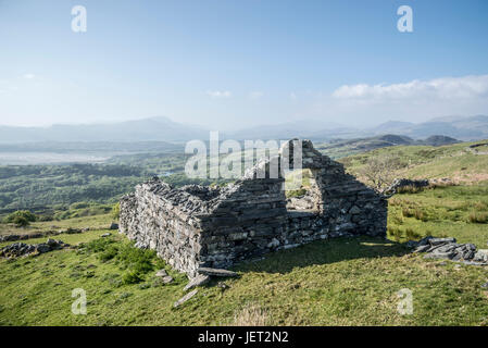 Alte Stein Bauernhof in den Hügeln in der Nähe von Harlech in Snowdonia, Nordwales. Dramatischen Blick auf die Berge an einem hellen Nachmittag. Stockfoto