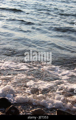 Kieselsteine am Strand mit Welle Stockfoto