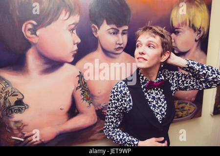 Kaukasische Mädchen mit androgynen Eigenschaften trägt festliche Kleidung in einem städtischen Umfeld Stockfoto