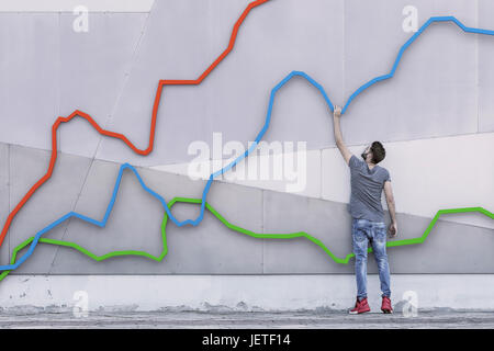 Ein junger Mann hält sich an ein Diagramm wie es steigt nach oben zeigt Wachstum in einem Markt und seinen Aufstieg, Rückverfolgung der Finanzmärkte Stockfoto