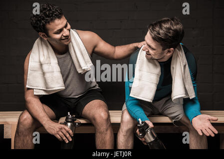 Gut aussehend männlichen Athleten ausruhen und unterhalten sich im Umkleideraum der Turnhalle Stockfoto