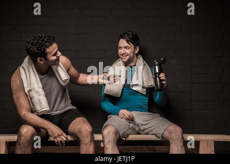 Gut aussehend männlichen Athleten ausruhen und unterhalten sich im Umkleideraum der Turnhalle Stockfoto