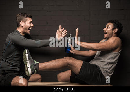 Gut aussehend männlichen Athleten ausruhen und unterhalten sich im Umkleideraum der Turnhalle Stockfoto