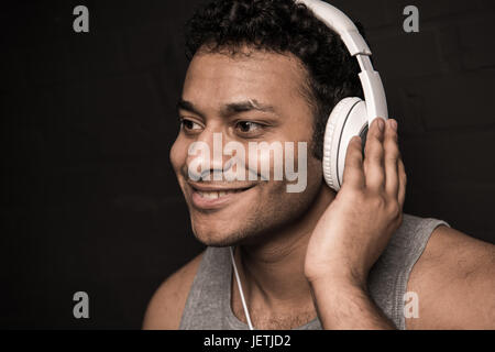 Hübscher junger Mann hören von Musik im Kopfhörer, isoliert auf schwarz Stockfoto